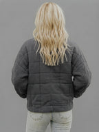 Back view of the Anouska oversized quilted jacket in dark grey, showcasing its relaxed fit, quilted design, long sleeves, and cozy winter-ready silhouette.