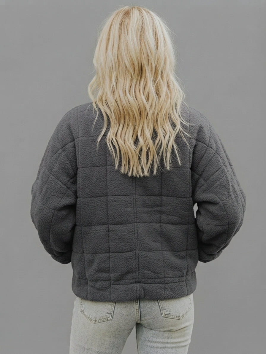 Back view of the Anouska oversized quilted jacket in dark grey, showcasing its relaxed fit, quilted design, long sleeves, and cozy winter-ready silhouette.