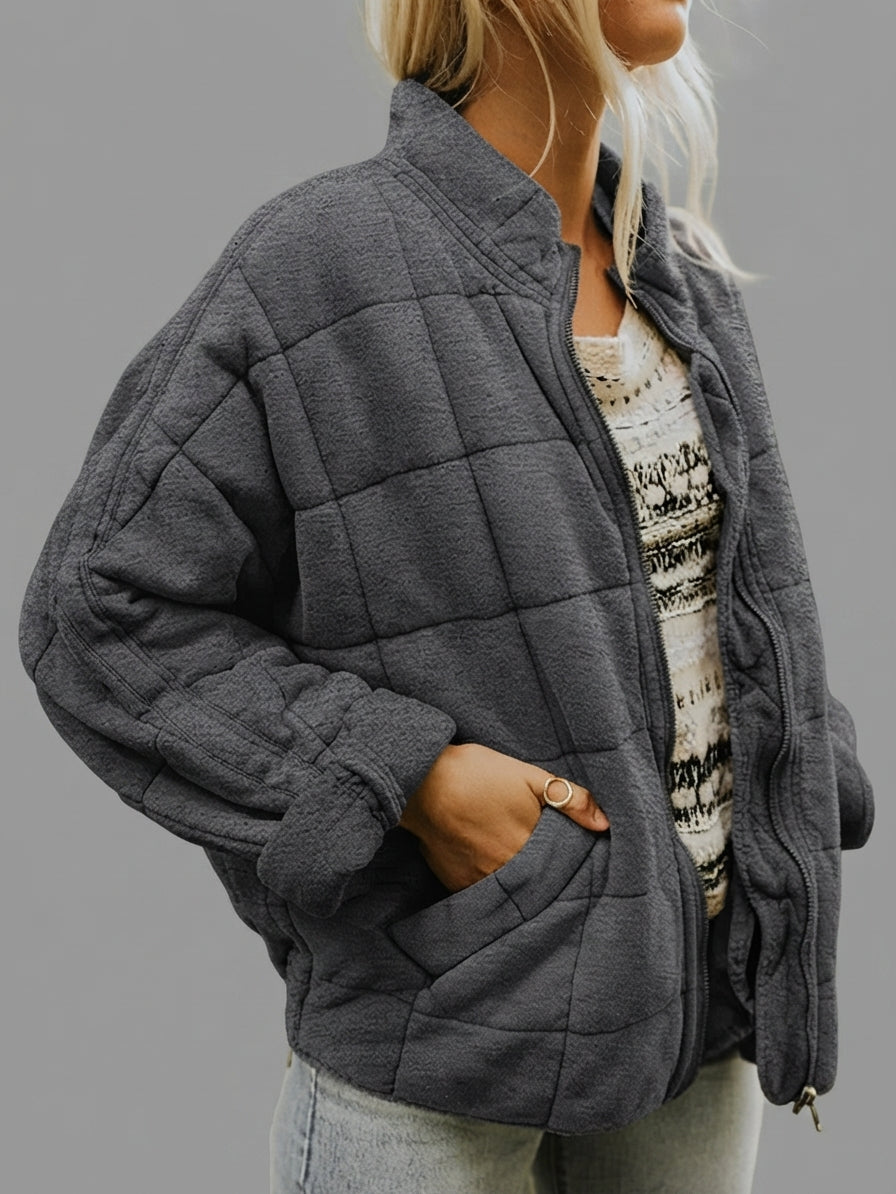 Front view of the Anouska Jacket Quilted Oversized in dark grey, showcasing its quilted design, oversized relaxed fit, long sleeves, and practical front pockets.