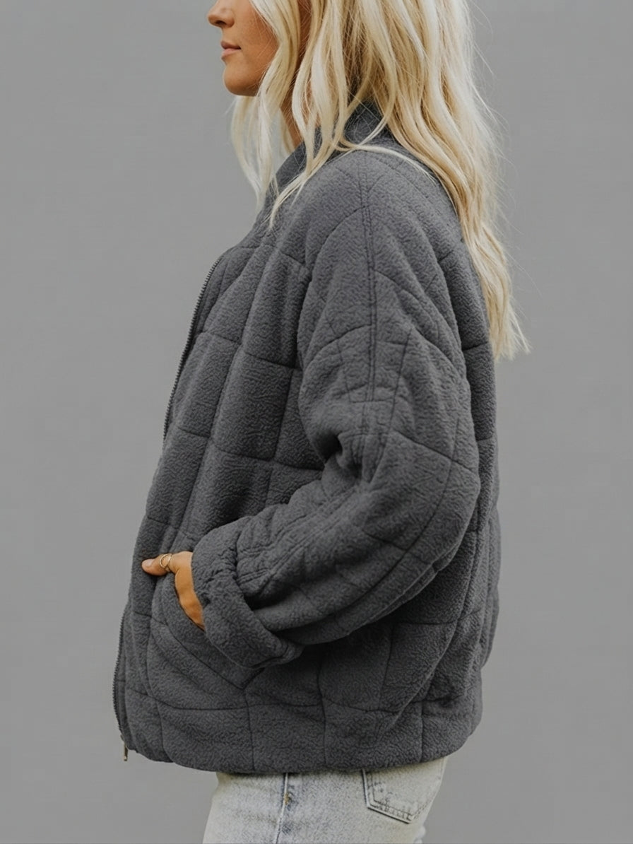 Side view of the Anouska Jacket Quilted Oversized in dark grey, showcasing its relaxed oversized fit, quilted design, long sleeves, and cozy cold-weather style.
