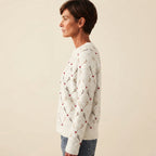 Side view of the white Béatrix Reindeer-Print Crew-Neck Sweater featuring a festive reindeer print, long sleeves, and a relaxed cozy fit.