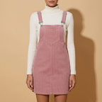 Front view of the blush pink Elodie Corduroy Pinafore Mini Dress featuring adjustable buckle straps, straight fit, and ribbed texture.