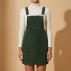 Front view of the forest green Elodie Corduroy Pinafore Mini Dress featuring metal buckle straps, mini silhouette, and bib pocket.