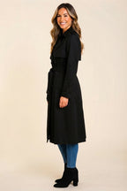 Side view highlighting the black color, soft wool-blend fabric, structured profile, long sleeves, and adjustable belted waist for a polished cold-weather look.