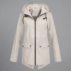 Front view of the Julia Rain Jacket in a soft cream color, featuring an attached hood, full zip-front closure, long sleeves, and practical front pockets. The lightweight design offers a clean, versatile look for rainy days, outdoor activities, travel, and everyday wear.