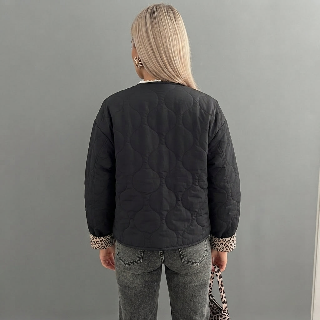 Back side view of the Sylvaine Jacket Quilted Leopard-Trim in black, highlighting its quilted texture, leopard-print trim, long sleeves, and relaxed silhouette.
