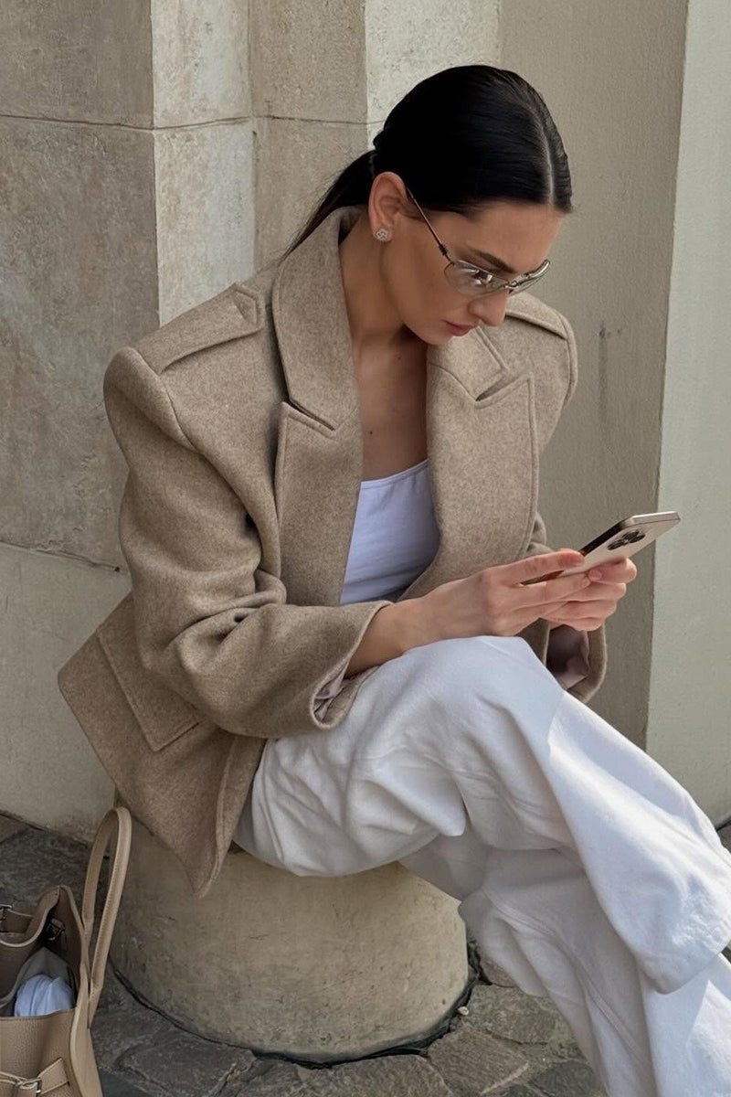 Adele Beige wide-lapel short jacket shown seated with oversized lapels, structured shoulders, and relaxed tailoring