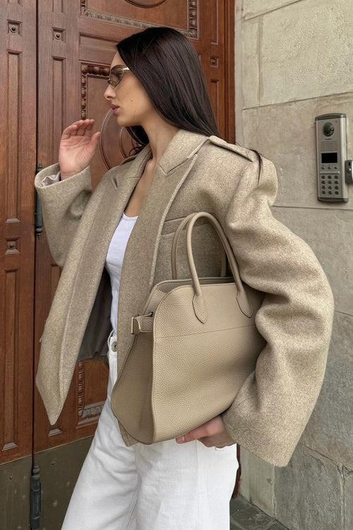 Adele Beige short jacket worn open over a white top and white pants, shown from the side with structured shoulders.