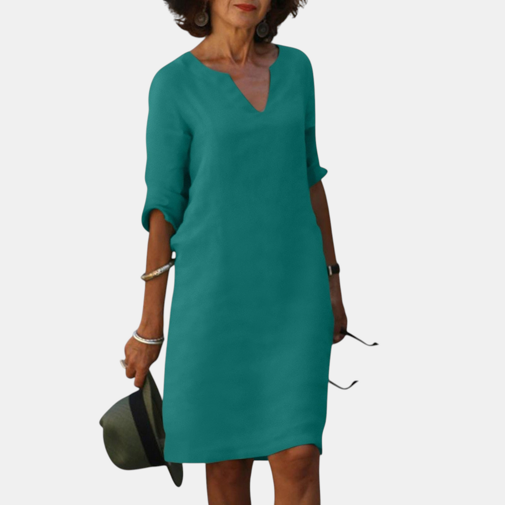 Front view of the Adele Shift Dress Lightweight V-Neck Half-Sleeve in dark green, featuring a V-neckline, half sleeves, side pockets, and a relaxed lightweight silhouette. Designed by Bella Hudson.