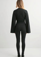 Alina Black wide-sleeve top seen from the back with ruched waist, styled with black leggings and heeled boots.
