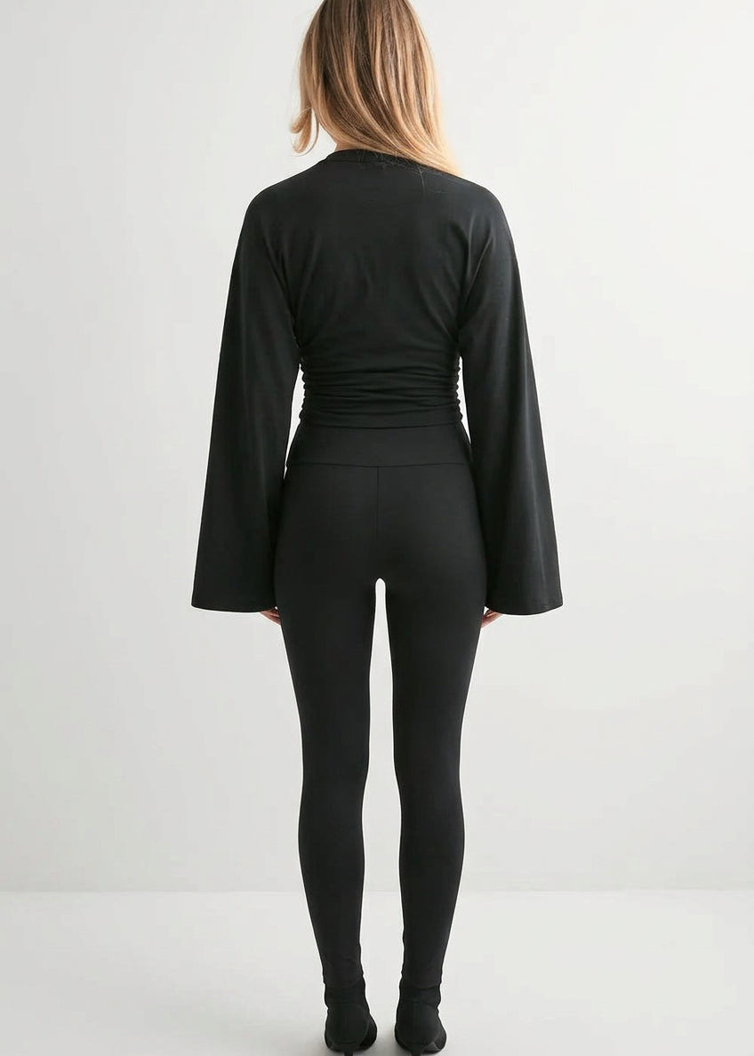 Alina Black wide-sleeve top seen from the back with ruched waist, styled with black leggings and heeled boots.