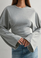 Alina Gray top close-up showing the crewneck, wide flared sleeves and gathered waist ruching with a denim skirt.