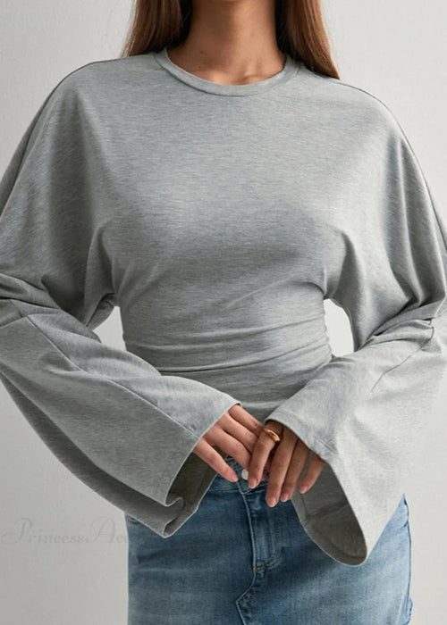 Alina Gray top close-up showing the crewneck, wide flared sleeves and gathered waist ruching with a denim skirt.