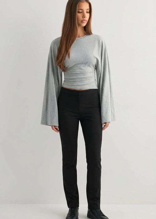 Alina Gray wide-sleeve top with flared sleeves and ruched waist styled with black slim pants and black sneakers.