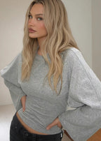 Alina Gray wide-sleeve top with a crew neckline and flared sleeves, styled with dark low-rise jeans.
