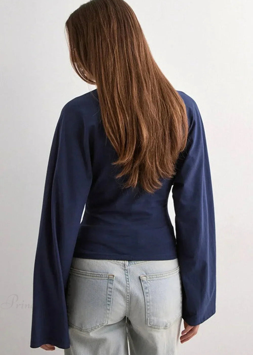 Alina Navy Blue wide-sleeve top seen from the back with long flared sleeves and light wash jeans.