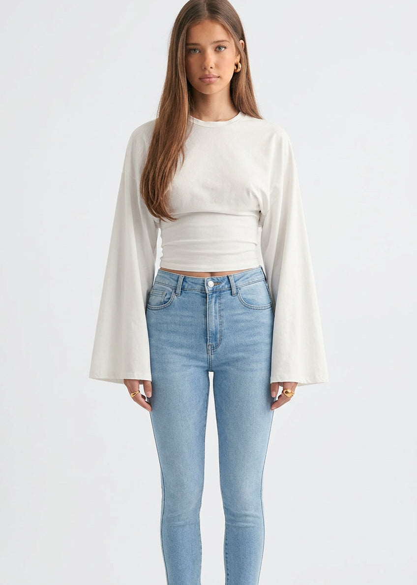 Alina White wide-sleeve top with a cropped length and ruched waist styled with light wash skinny jeans.