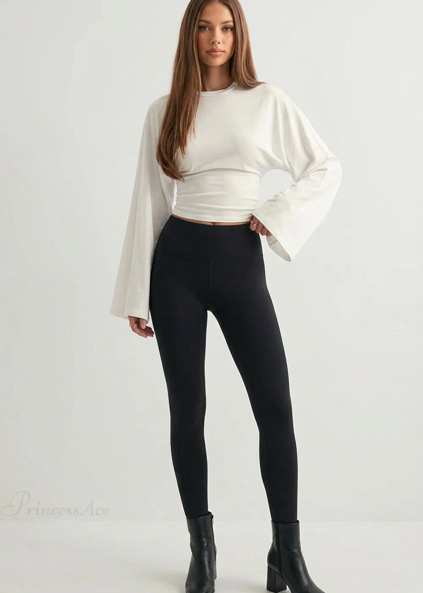 Alina White wide-sleeve top with ruched waist styled with black leggings and black ankle boots.