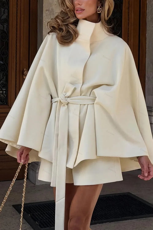 Amalia Beige belted cape coat with wide sleeves and matching shorts, shown from the front with a chain bag.