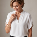 Close-up detail of the Amandine Blouse V-Neck Flowy Short-Sleeve in white, featuring the split V-neckline, soft draping, and lightweight fabric. Designed by Bella Hudson.