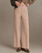 Anwen Khaki high-waisted wide-leg pants shown from the front with patch pockets and a button closure, styled with a knit cardigan.