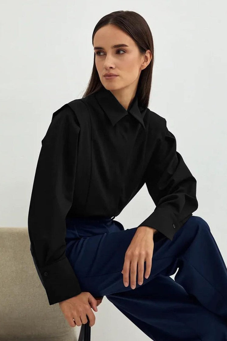 Ariana Black button-down shirt worn seated with navy wide-leg trousers, showing the point collar and buttoned cuffs.