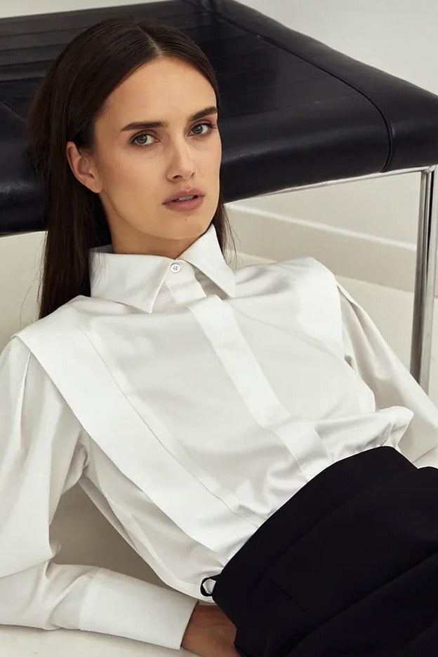 Ariana White button-down shirt buttoned up with a high collar and pleated shoulder panels, worn with black bottoms.