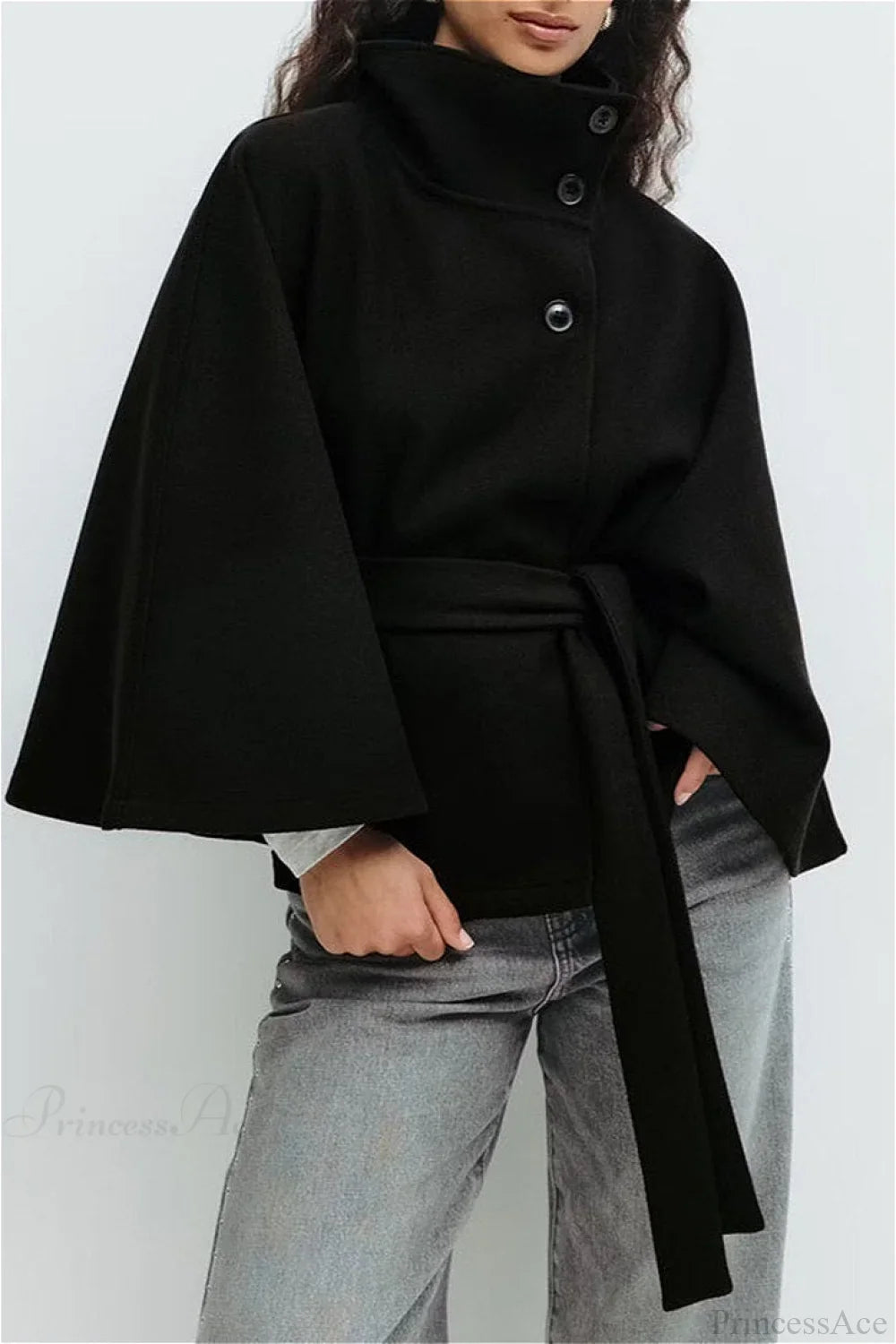 Arielle Black belted cape jacket styled with gray jeans, showing the buttoned stand collar and wide cape sleeves.