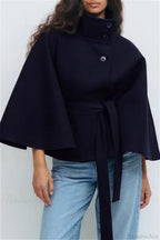 Arielle Navy Blue belted cape jacket styled with light-wash jeans, showing the stand collar, buttons and tied belt.