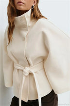 Arielle White belted cape jacket shown from the side with button stand collar and knotted self-tie belt.
