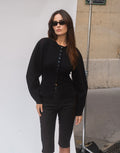 Aurelia Black button-front cardigan with balloon sleeves styled with sunglasses and black knee-length shorts outdoors.