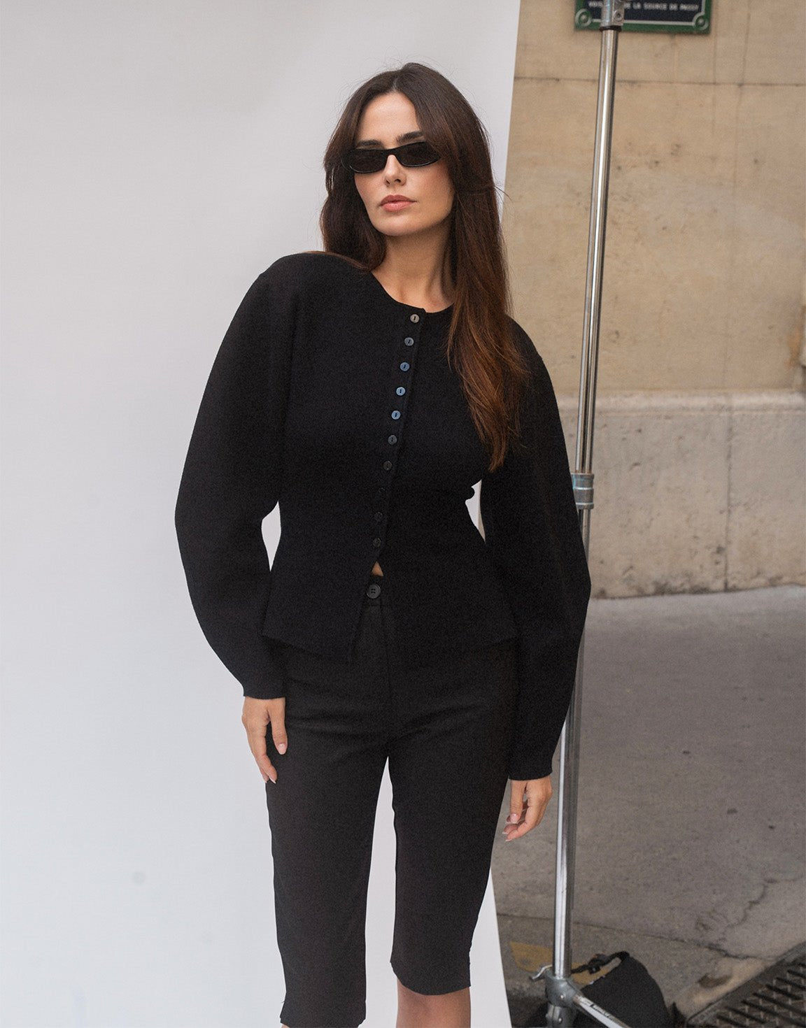 Aurelia Black button-front cardigan with balloon sleeves styled with sunglasses and black knee-length shorts outdoors.