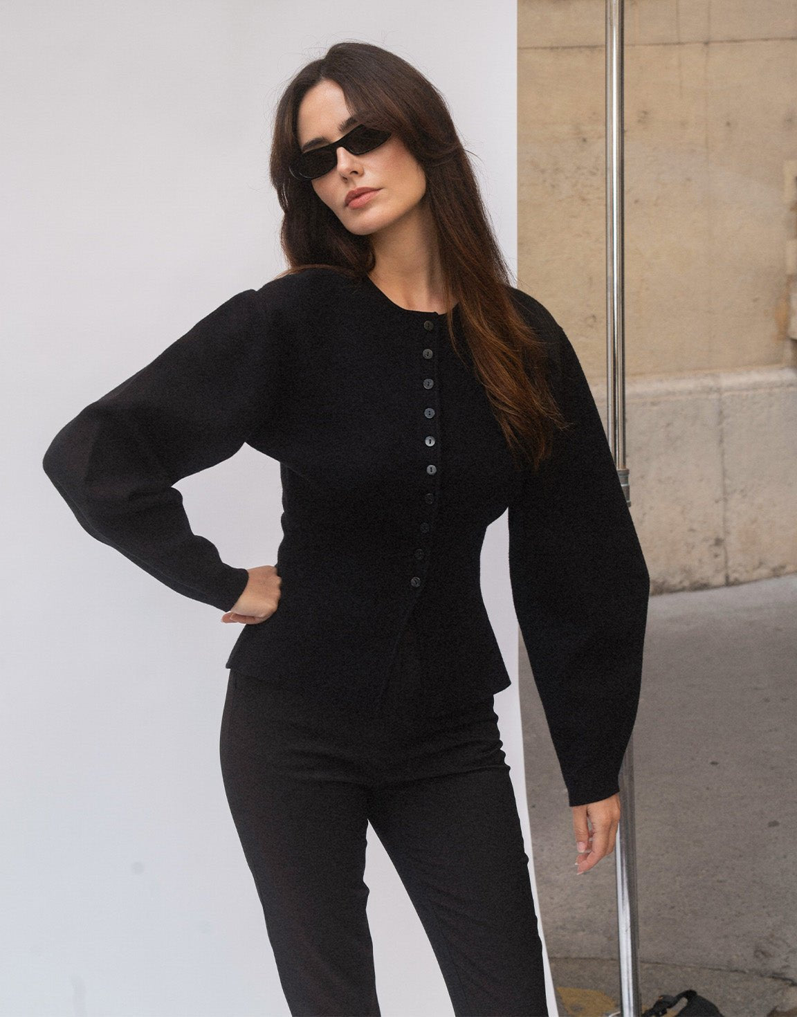 Aurelia Black cardigan shown from a three-quarter angle with one hand on the hip, highlighting the voluminous sleeves and button front.