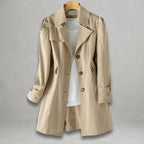 Front view of the Aurora Trench Coat with Belted Notch Collar in khaki, featuring wide notched lapels, a button-front closure, long sleeves with cuff straps, matching waist belt, and a flared mid-length silhouette. Designed by Bella Hudson.