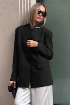 Aveline Black stand collar blazer with two-button front and flap pockets, styled with white trousers.