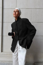 Aveline Black blazer with structured shoulders and relaxed fit, worn with white satin pants.
