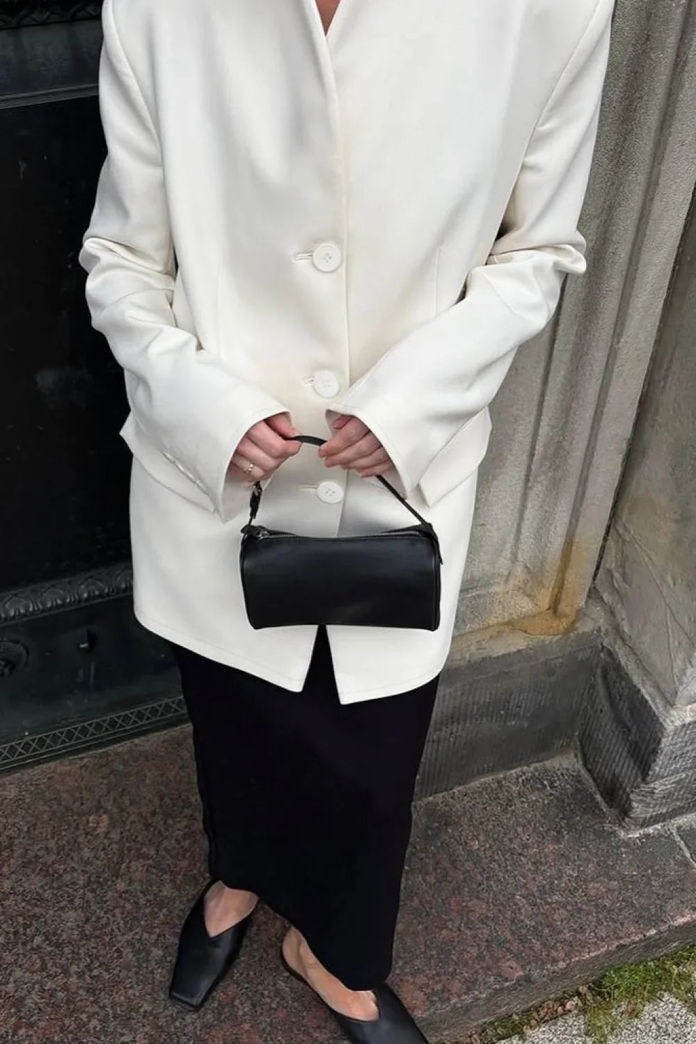Aveline White blazer close-up of the button front and long sleeves with a black bag.