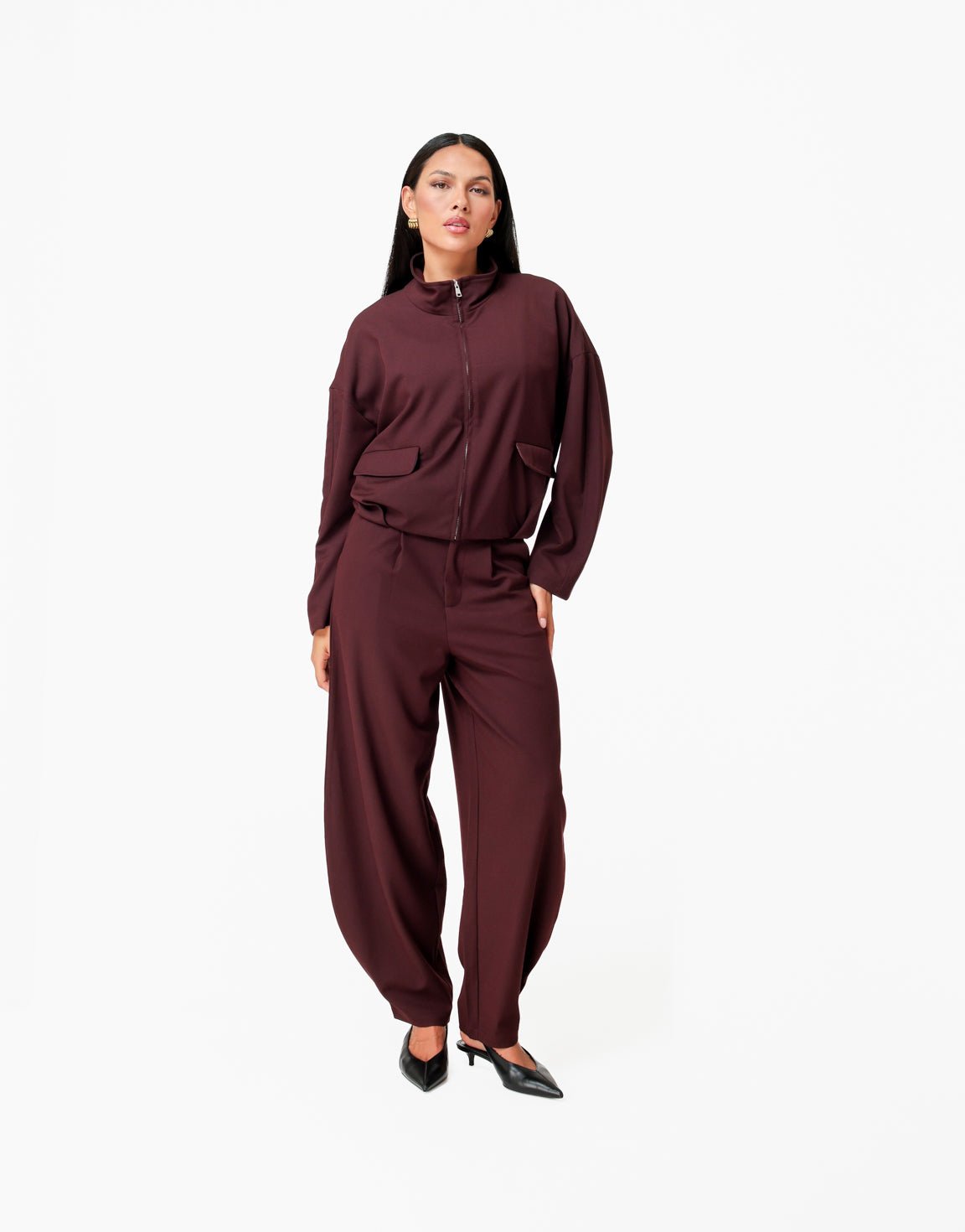 Averil Aubergine bomber jacket full-body look worn with matching wide-leg trousers and black slingback heels.