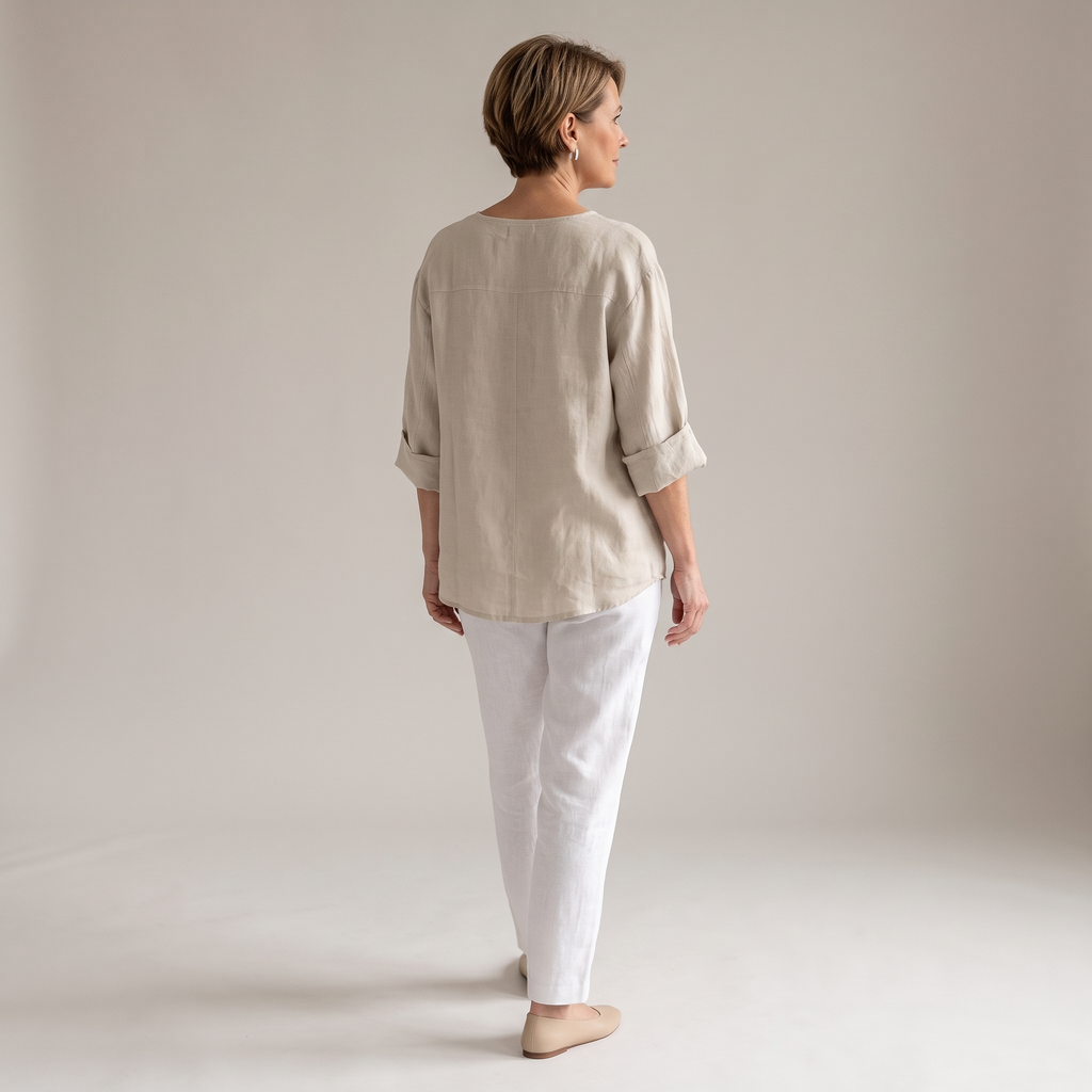 Back view of the Averil Blouse Linen Long-Sleeve in beige, highlighting the relaxed silhouette, long rolled sleeves, and lightweight linen construction. Designed by Bella Hudson.