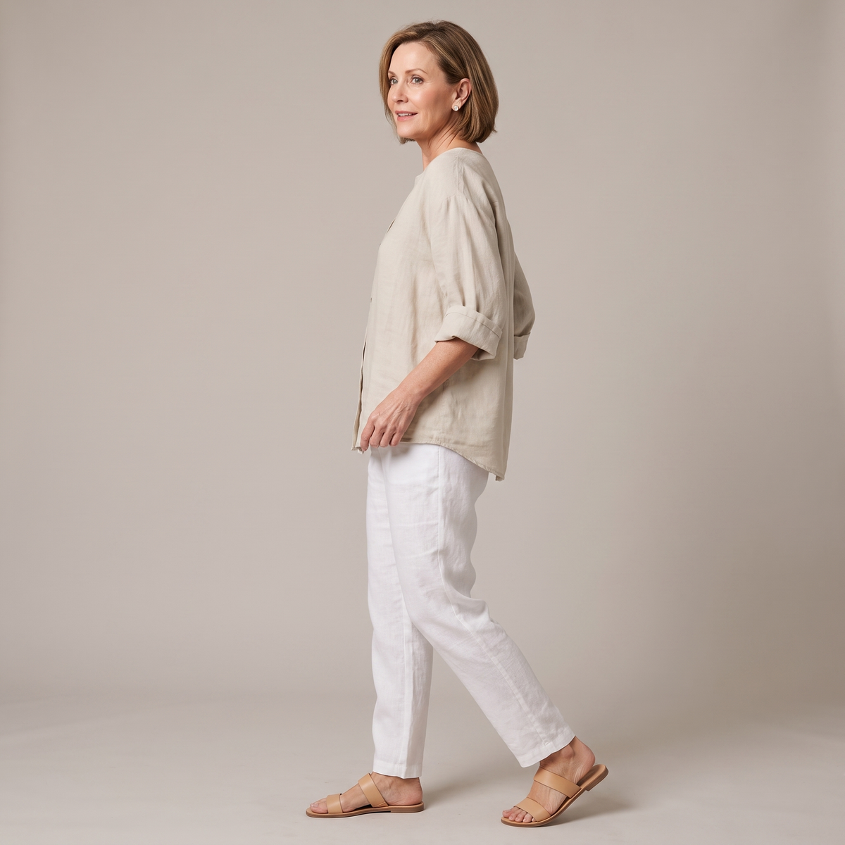 Side view of the Averil Blouse Linen Long-Sleeve in beige, showcasing the relaxed fit, rolled long sleeves, split V-neckline, and breathable linen fabric. Designed by Bella Hudson.