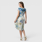 Back view of the Bianca Midi Lightweight Dress Watercolor-Print Cowl-Neck in sky blue, highlighting the graceful drape, cap sleeves, watercolor floral print, and elegant midi-length silhouette. Designed by Bella Hudson.
