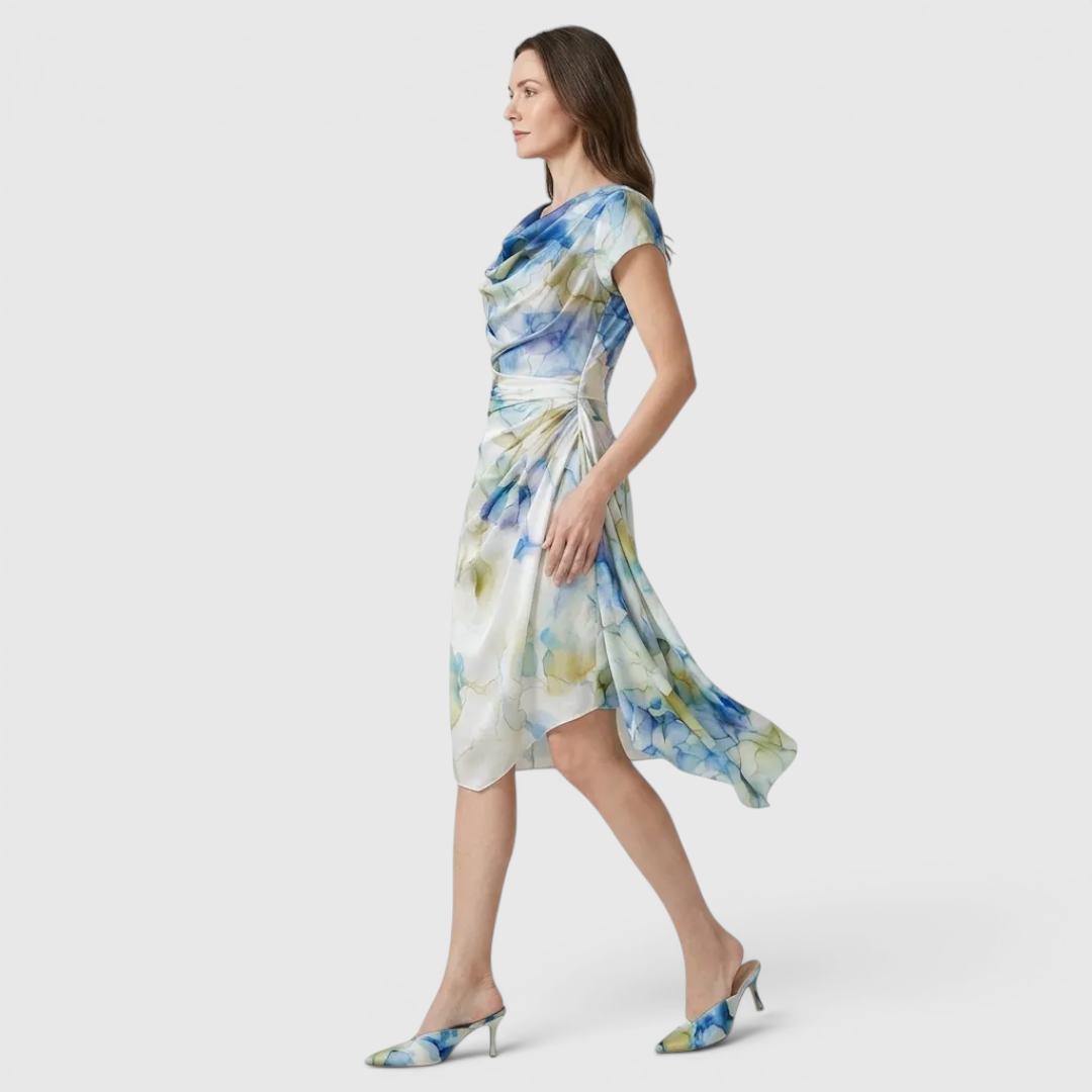 Side view of the Bianca Midi Lightweight Dress Watercolor-Print Cowl-Neck in sky blue, showcasing the draped cowl neckline, cap sleeves, flowing asymmetrical hem, and soft watercolor print. Designed by Bella Hudson.
