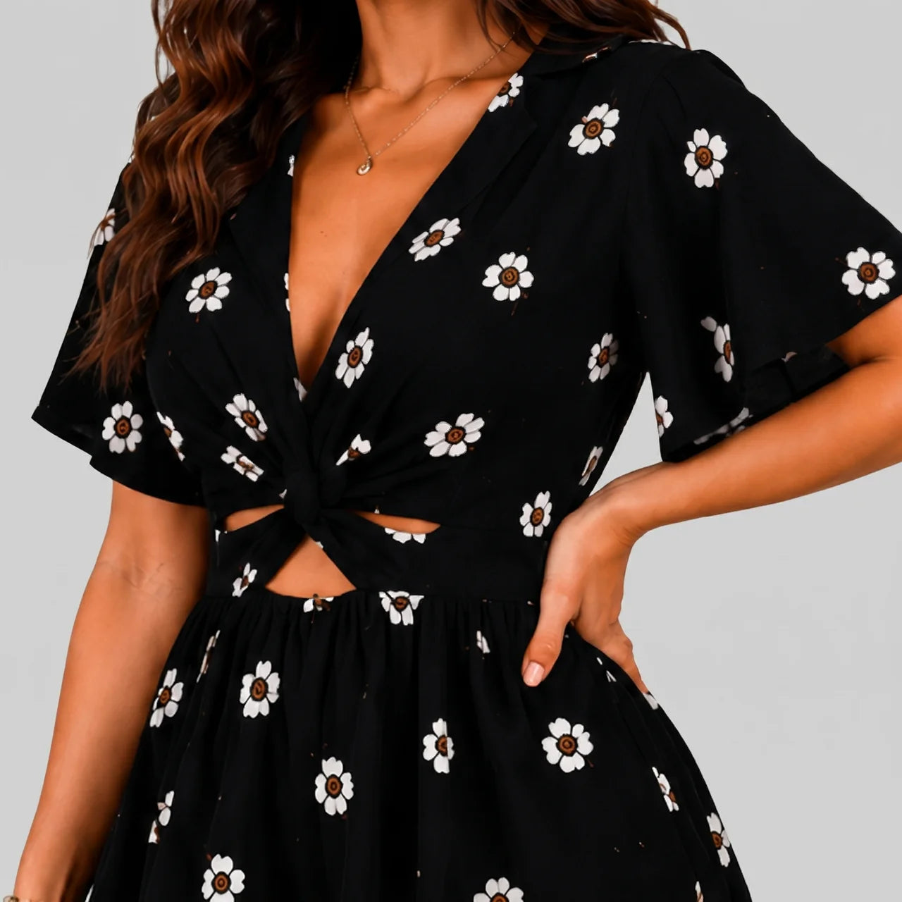 Close-up view of black floral romper with short sleeves and tie waist detail by BELLA HUDSON
