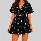 Front view of black floral romper with short sleeves and tie waist detail by BELLA HUDSON