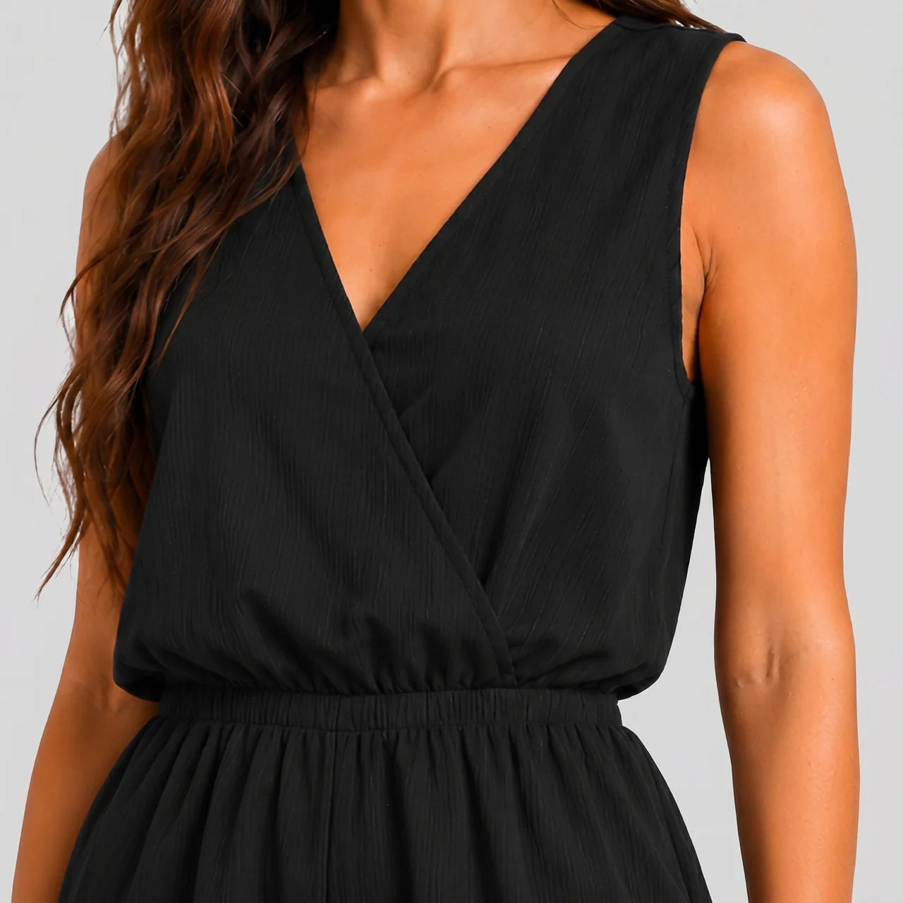 Close-up detail view of black sleeveless wrap jumpsuit with V-neckline by BELLA HUDSON