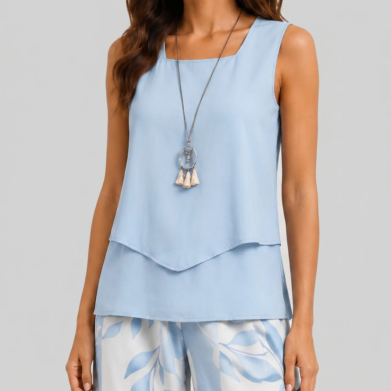 Close-up view of blue layered sleeveless top and wide leg pants set with floral print by BELLA HUDSON