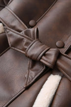 Brielle Brown faux leather jacket close-up of the tied waist belt, covered buttons, and cream faux shearling trim.