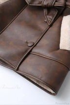 Brielle Brown faux leather jacket detail showing covered buttons, contrast piping, cuff trim, and soft cream faux shearling lining.