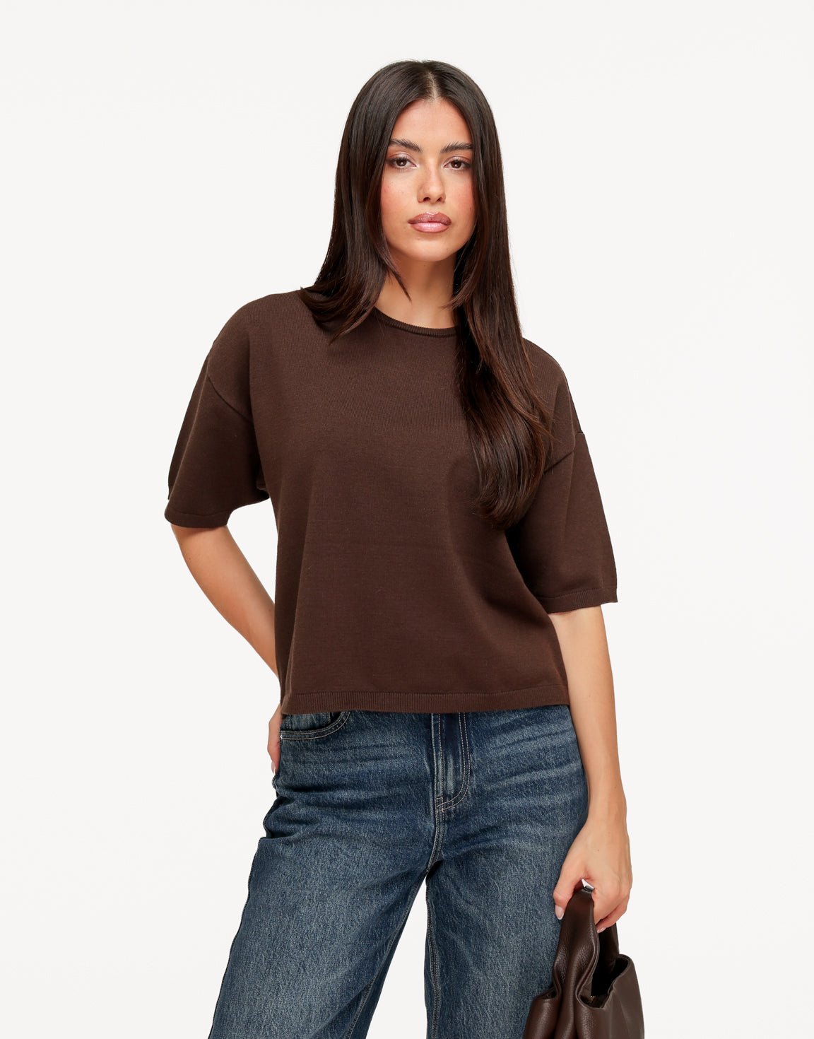 Briony Brown knit T-shirt worn with dark wash jeans, shown from the front with a brown handbag.