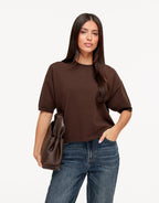 Briony Brown short sleeve knit T-shirt styled with jeans and a brown leather tote, with one hand in the pocket.